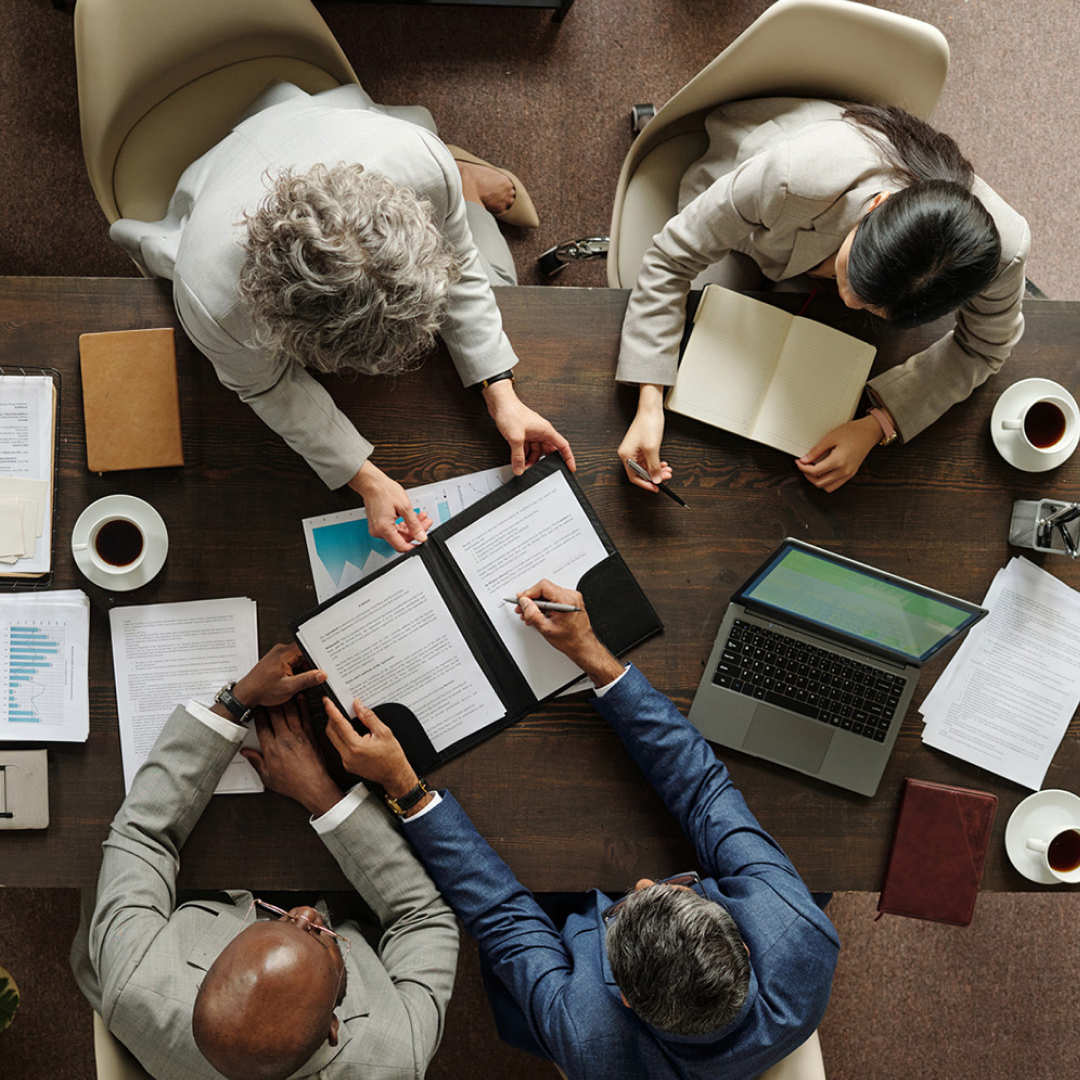Business professionals collaborating around a table with financial documents and a laptop.